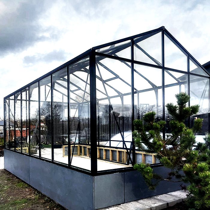Black wall-mounted glass greenhouse beside a home